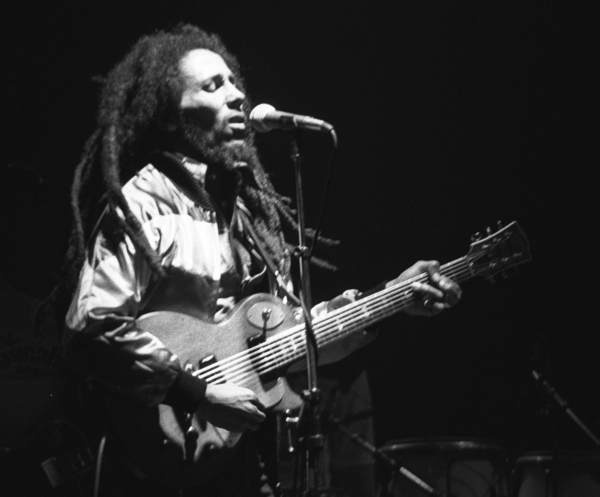 Ein schwarz-weiß-Foto von Bob Marley mit langen Rastazöpfen und E-Gitarre