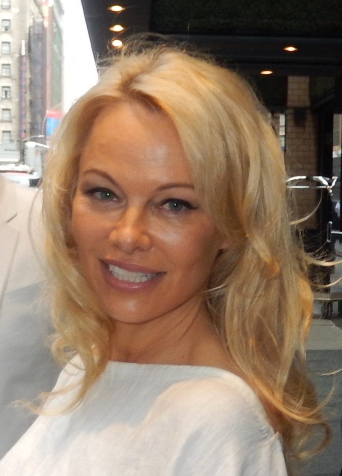 Pamela Anderson mit schulterlangen, blonden Haaren in einem schlichten Shirt.