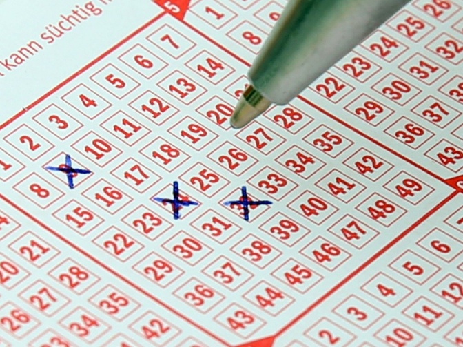 Ein Lottoschein, auf dem 3 Zahlen mit Kuli angekreuzt sind.