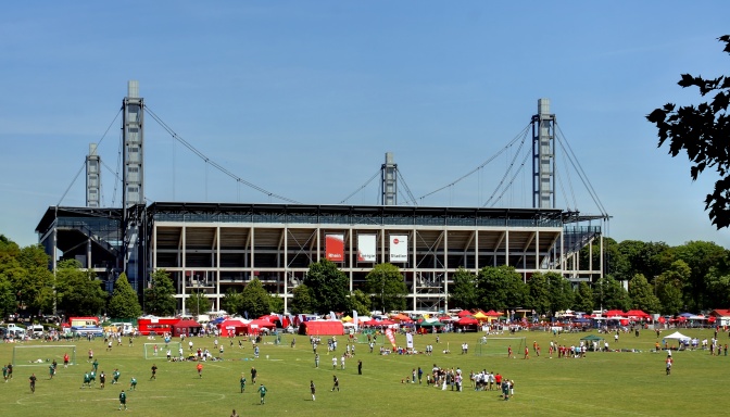 Die Südseite des Kölner Stadions mit einer großen Wiese und vielen Menschen davor.
