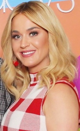 Katy Perry mit blonden gewellten Haaren in einem karierten Kleid.