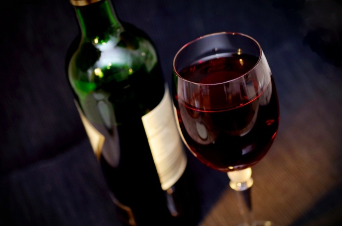 Eine Flasche Rotwein mit einem gefüllten Glas daneben.