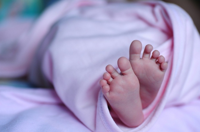 Ein Säugling mit nackten Füßen, in ein Tuch gewickelt.