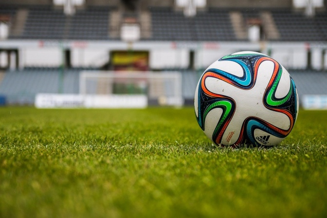 Ein Fußball liegt in einem leeren Stadion auf dem Rasen.