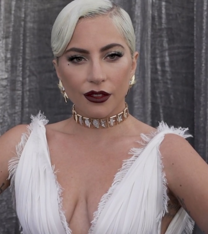 Lady Gaga  in einem eleganten weißen Kleid mit einem Chocker und blonder, zur Wasserwelle gelegten Haaren