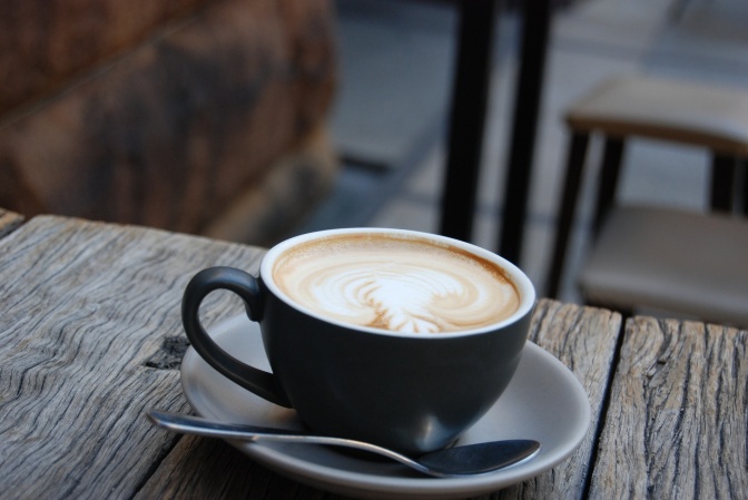 Eine Tasse Cappuccino mit Muster im Milchschaum auf einer hölzernen Tischplatte