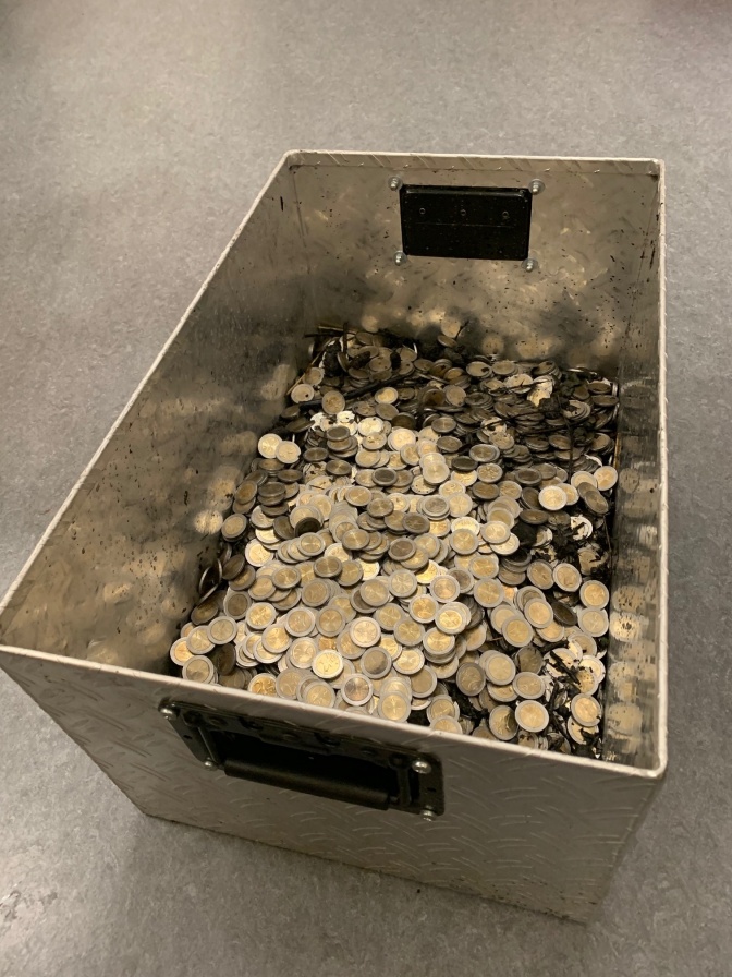 Eine große Metallkiste zu etwa einem Drittel gefüllt mit Euomünzen