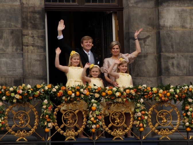 Die niederländische Königsfamilie steht auf einem Balkon und winkt.