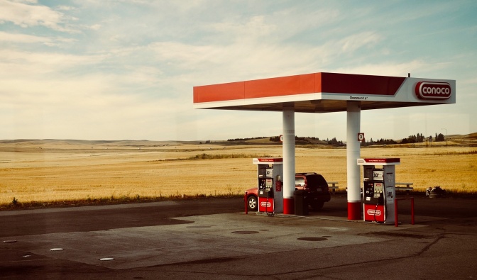 Ein Auto steht an einer Tankstelle inmitten von Getreidefeldern