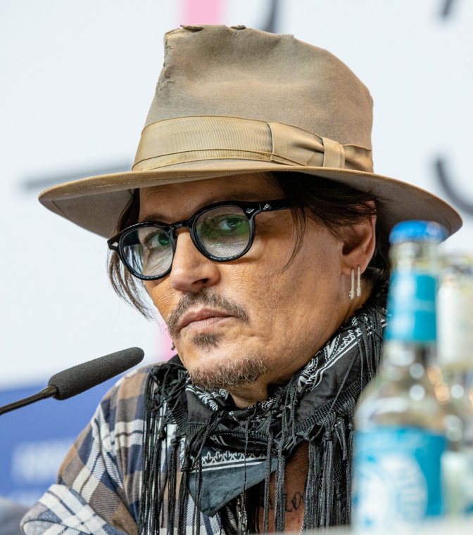 Johnny Depp mit Hut und getönter Brille. Er trägt Schnäuze und einen kleinen Kinnbart.