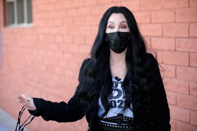 Cher mit langen, glatten schwarzen Haaren und schwarzer Gesichtsmaske
