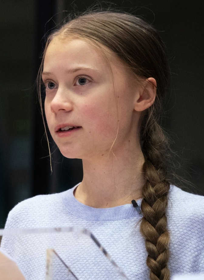 Greta Thunberg mit langen, glatten geflochtenen Haaren. Sie trägt ein T-Shirt.