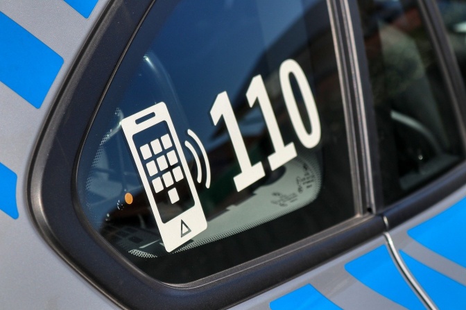 Die Notrufnummer 110 auf der Seitenscheibe eines Polizeiautos.