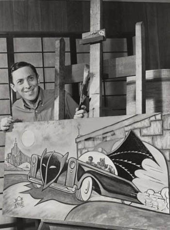 Bob Kane hält eine große Zeichnung von Batman und Robin im Batmobil in der Hand. Das Foto ist schwarz-weiß.