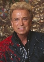 Siegfried Fischbacher mit blonden nach hinten geföhnten Haaren in einer rot-schwarzen Jacke.