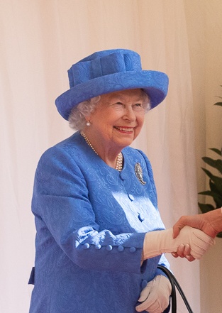 Queen Elisabeth in einem hellblauen Kostüm mit farblich passendem Hut und Handtasche.