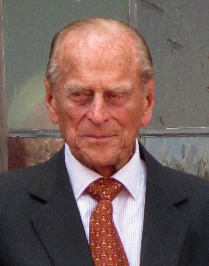 Prinz Philip mit Halbglatze und rötlichem Haarkranz. Er trägt Anzug und Krawatte.
