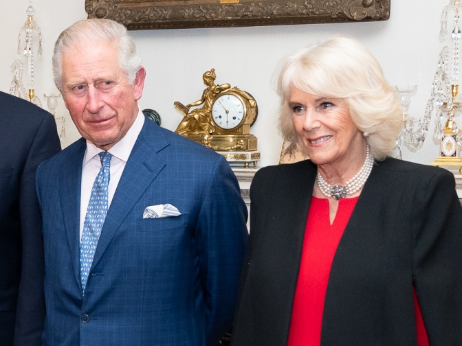 Prinz Charles in Anzug und Krawatte und Herzogin Camilla in Bluse und Sakko mit Perlenschmuck.