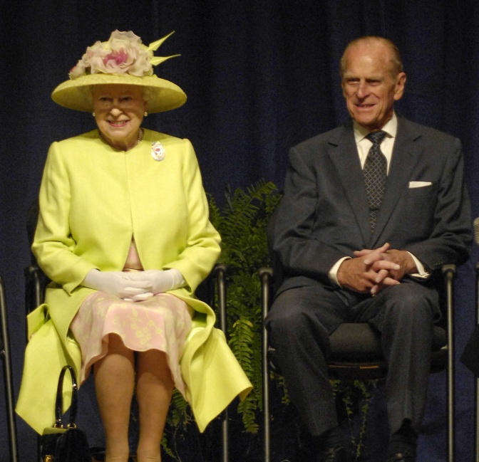Prinz Philip und die Queen in festlicher Kleidung auf 2 Stühlen sitzend