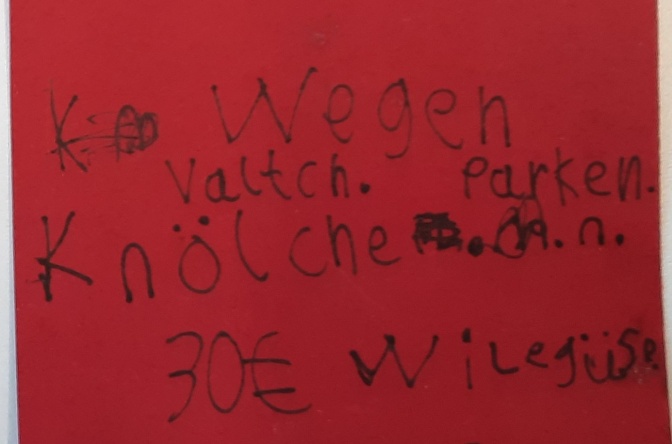 Ein Zettel, auf dem in schiefen, handgeschriebenen Buchstaben steht: Wegen Valtch Parken Knölche 30 Euro Wilegüse.