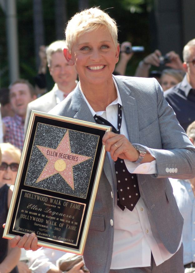 Ellen deGeneres mit kurzen, blonden Haaren. Sie lächelt und hält einen Bilderrahmen mit einem Stern, auf dem ihr Name steht, in der Hand.