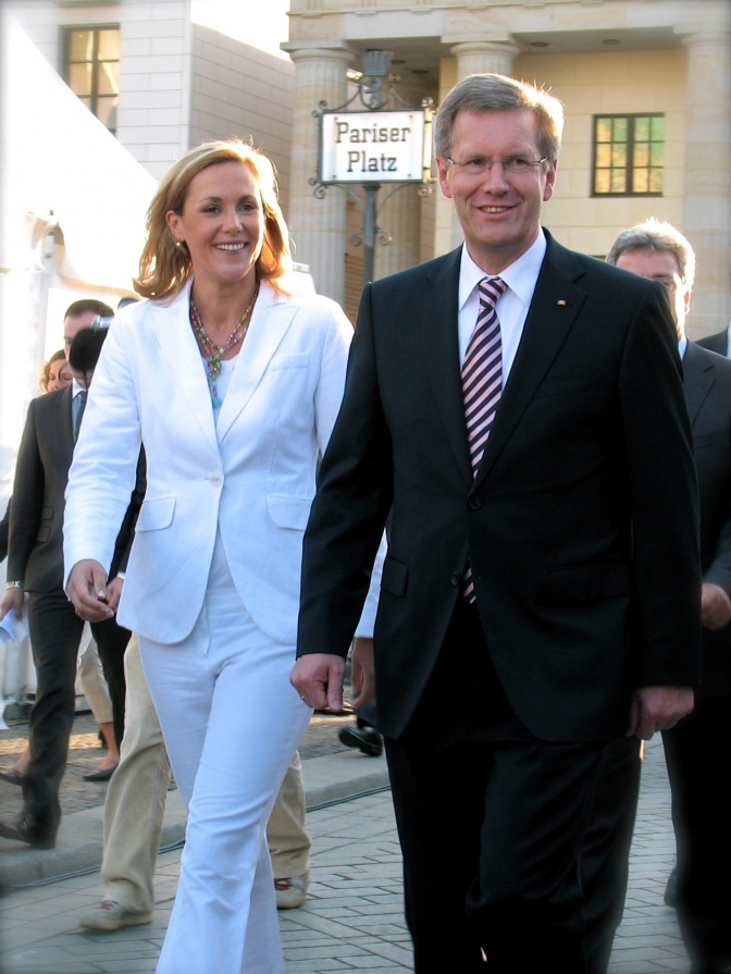 Bettina Wulff trägt einen weißen Anzug und hält Händchen mit. und Christian Wulff.