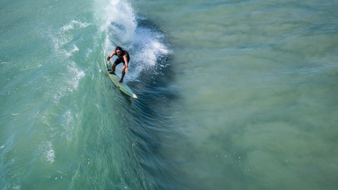 Ein Surfer surft auf einer Welle grünlichen Wassers mit Gischt