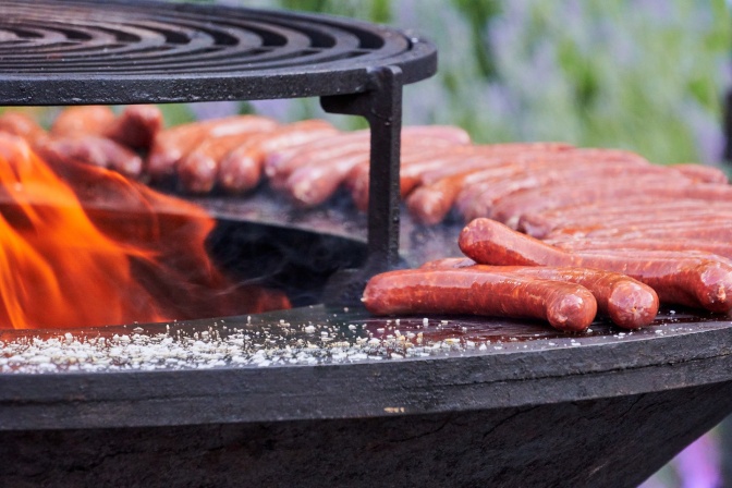 Viele Bratwürste auf einem Grill mit offenem Feuer