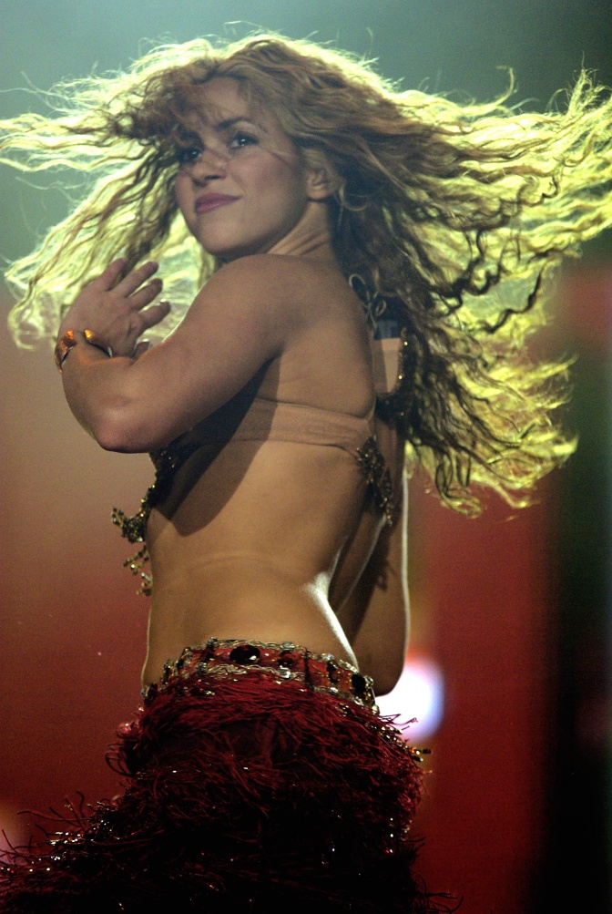 Shakira tanzt mit wirbelnden Haaren in einem rückenfreien Oberteil.