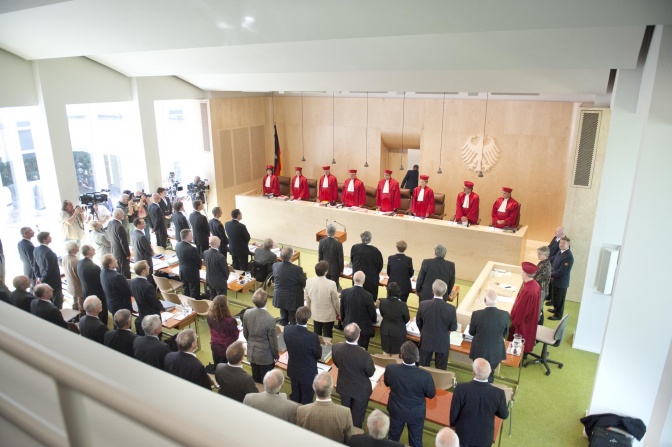 Beginn einer Verhandlung im Bundesverfassungsgericht. Alle Anwesenden stehen, zu forderst 8 Richter und Richterinnen in roten Roben.