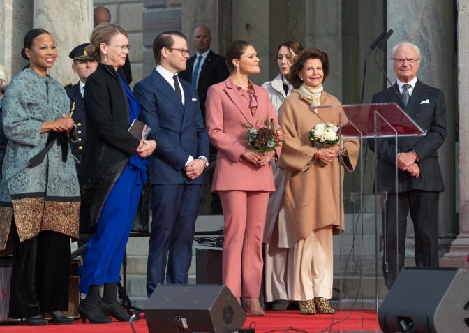 Die schwedische Königsfamilie steht auf einer Bühne. Alle lächeln, die Frauen halten Blumen in der Hand