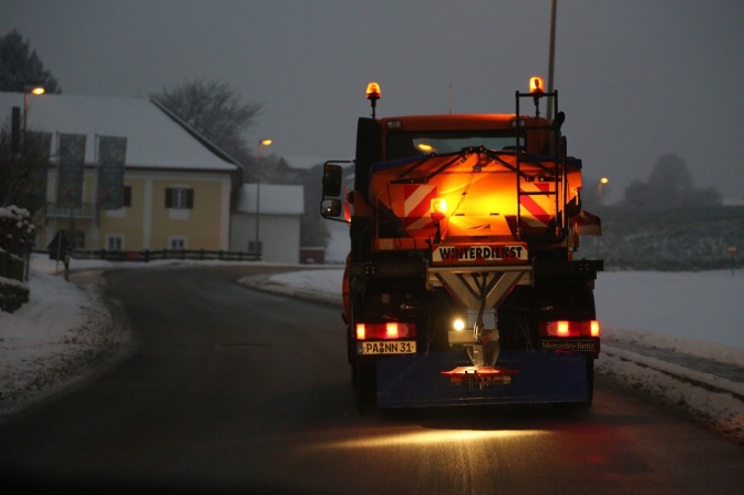 Ein Fahrzeug des Winterdienstes streut Salz auf der Straße.