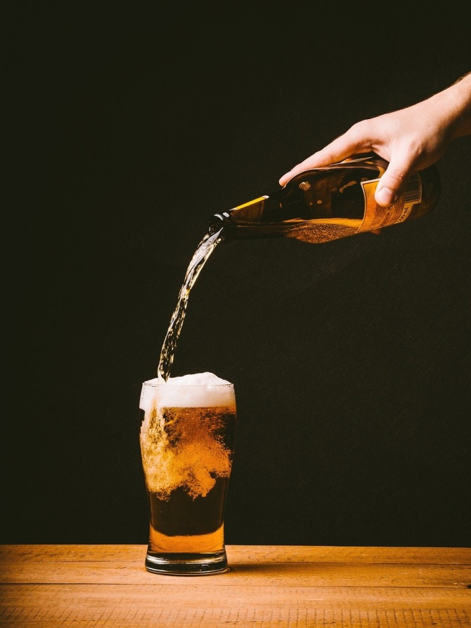 Ein Glas Bier wird aus einer Bierflasche eingegossen.