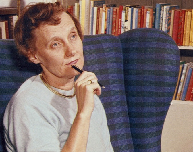 Astrid Lindgren sitzt mit nachdenklichem Blick in einem Sessel vor einem Bücherregal und hat einen Stift in der Hand.