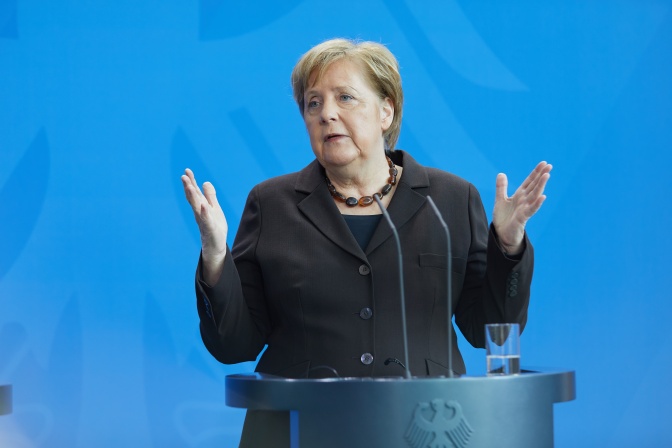 Angela Merkel steht vor einem Mikrophon und hält eine Rede. Dabei gestikuliert sie mit den Händen.