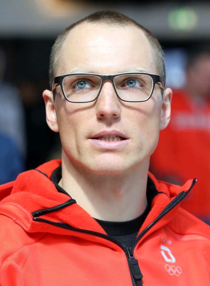 Erik Lesser in einer Trikotjacke mit schwarzer Brille und Stirnglatze