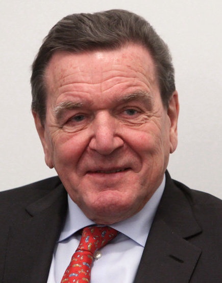 Gerhard Schröder mit Falten im Gesicht und braunen Haaren, Er trägt Anzug und Krawatte.
