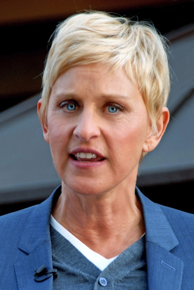 Ellen DeGeneres mit kurzen, hellblonden Haaren in einem blauen Sakko.
