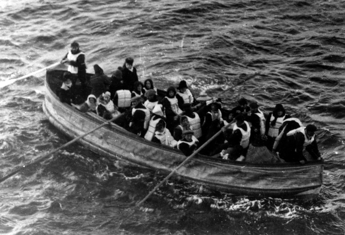 Schwarz-weiß Foto eines Rettungsboot mit 26 Passagieren der Titanic, zum Teil in Rettungswesten. Mehrere Männer rudern.
