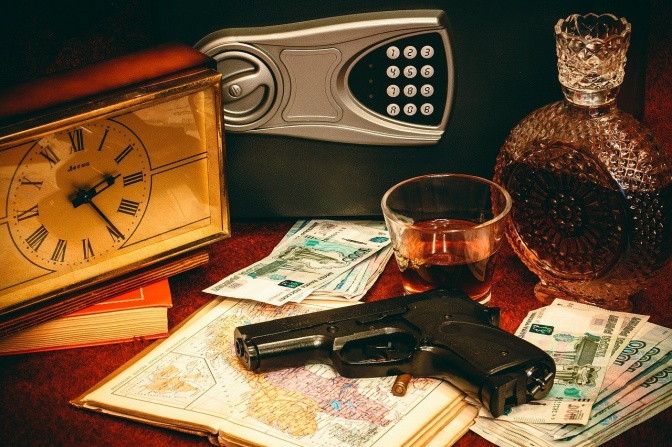 Eine Pistole liegt auf einem Bündel Rubelscheine, daneben ein Wecker und ein geöffneter Safe
