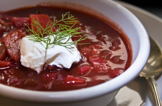 Ein Teller mit Suppe aus Roter Bete und Kohl, garniert mit einem Klecks Saurer Sahne und frischem Dill.