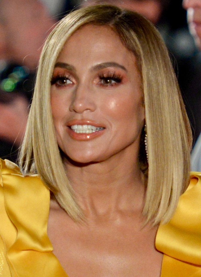 Jennifer Lopez mit blondierten schulterlangen Haaren in einem festlichen gelben Kleid