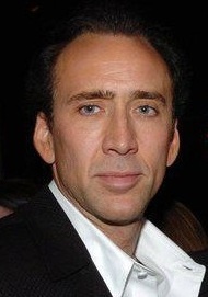 Nicolas Cage in weißem Hemd und Sakko. Er schaut mit ernstem Gesicht in die Kamera.
