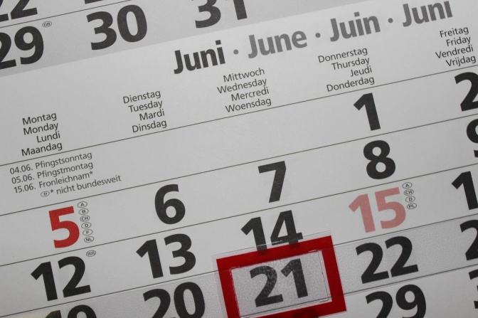 Ein Wandkalender, aufgeschlagen im Monat Juni. Ein roter Schieberegler aus Plastik markiert den aktuellen Tag.