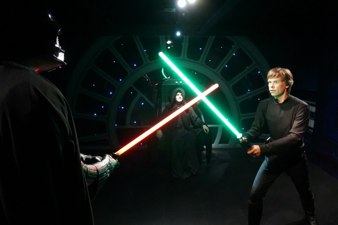 Luke Skywalker und Darth Vader mit gekreuzten Laserschwertern, dahinter der Imperator. Eine Szene aus dem Film Die Rückkehr der Jedi-Ritter.