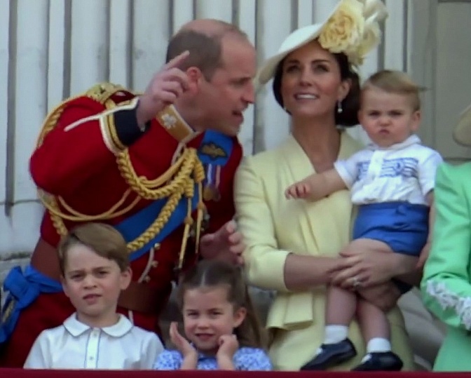Prinz William und Herzogin Kate stehen mit ihren 3 Kindern auf dem Balkon des Palastes. Alle tragen festliche Kleidung, William trägt Uniform.