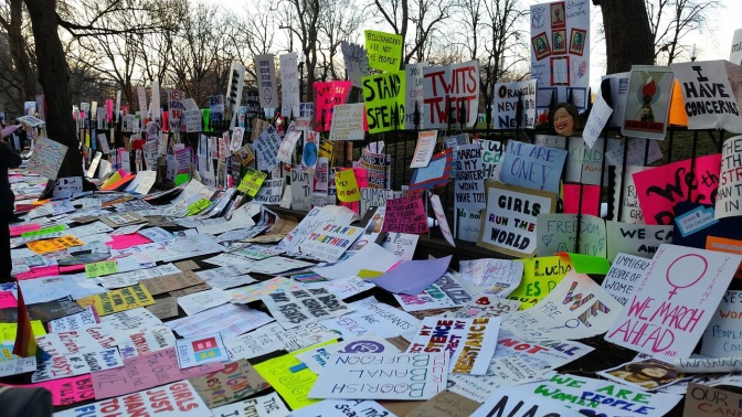 Sehr viele Protestplakate von Demos liegen auf dem Boden oder stehen an eine Mauer gelehnt.