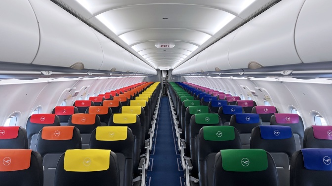 Sitze im Flugzeug mit Kopfstützen in Regenbogenfarben.