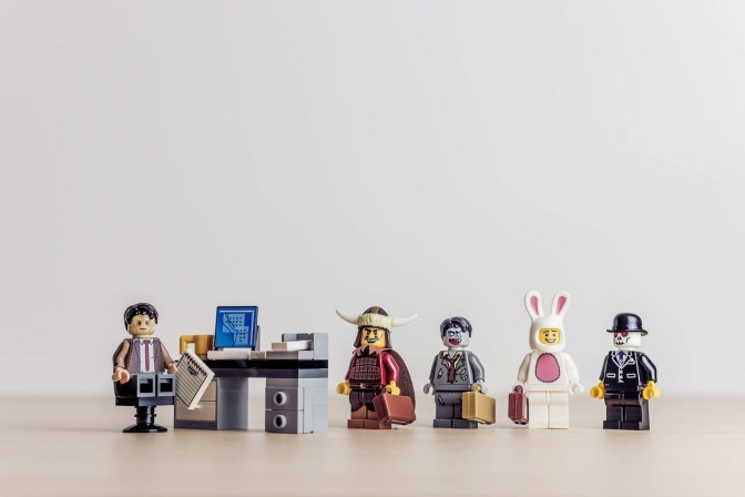 Mehrere Legofiguren, unter anderem ein Mann  in Anzug hinter einem Schreibtisch und ein weißer Hase mit Aktenkoffer.