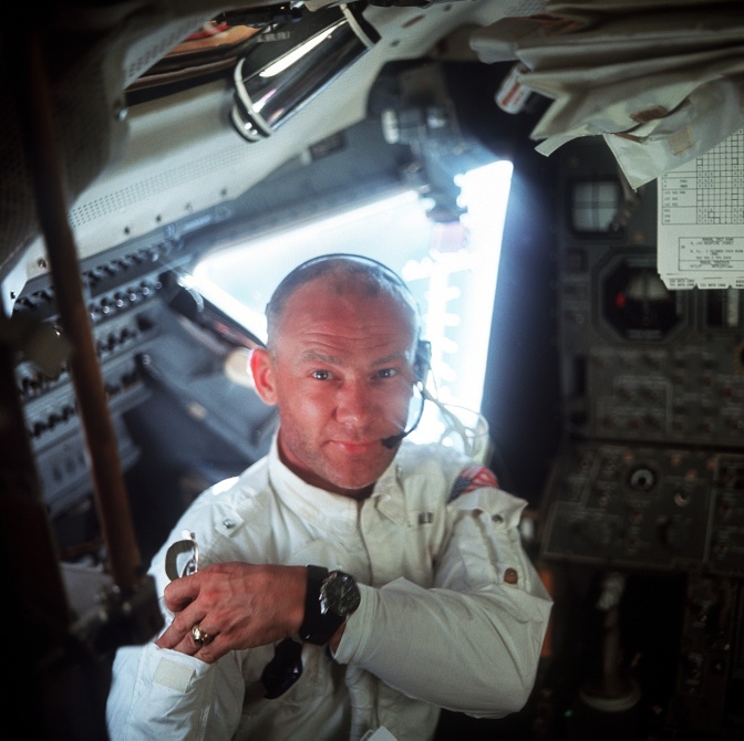 Buzz Aldrin in einem Weltraumanzug in einer Mondfähre. Er lächelt in die Kamera.